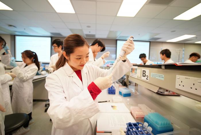 穿着实验室外套的学生在实验室使用设备