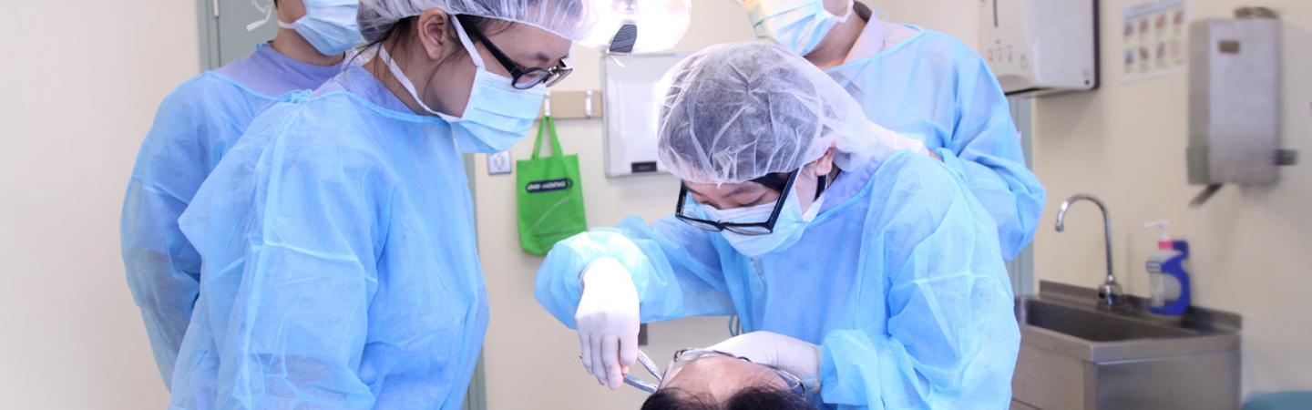 穿著醫用長袍的學生在病人身上使用牙科設備