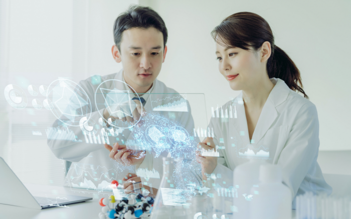 2 people in labcoat looking at futuristic icons floating in front of them