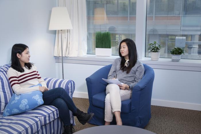 Students chatting in room while sitting on blue sofas