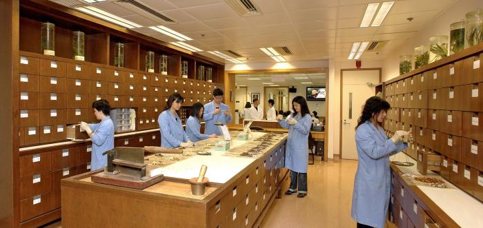 Students wearing medical gown looking at Chinese medicine ingredients