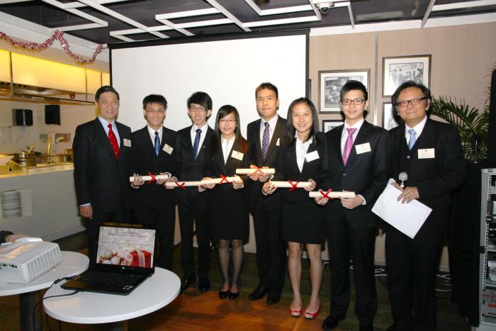 Students and professors in formal attire holding certificates
