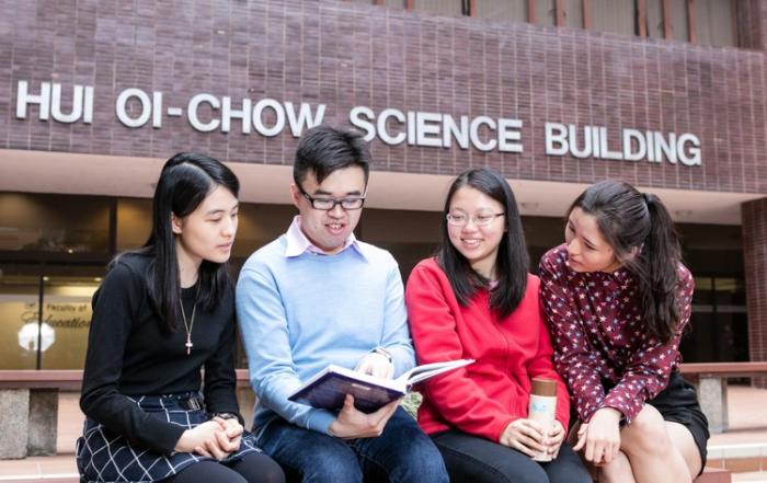 Four asian students are chatting in front of Hui Oi Chow Science Building