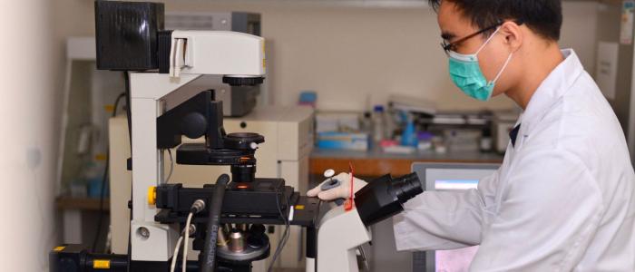 Student wearing labcoat working with equipment