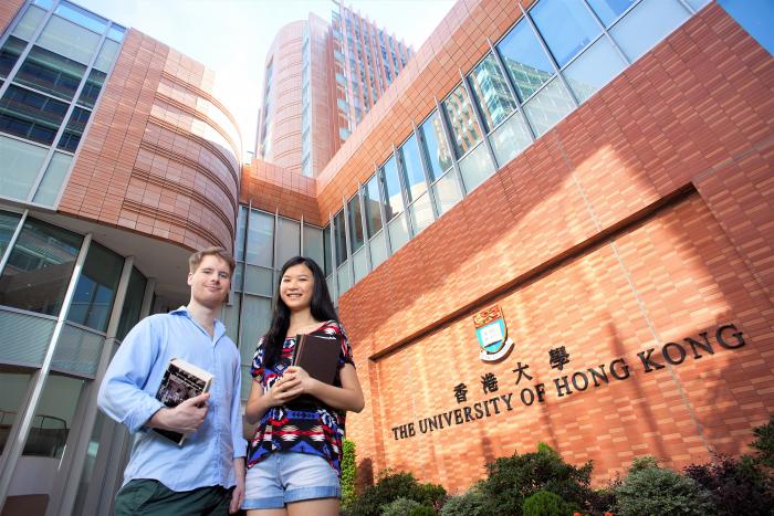 Students smiling in front of the University of Hong Kong Centennial Campus Red Brick Wall