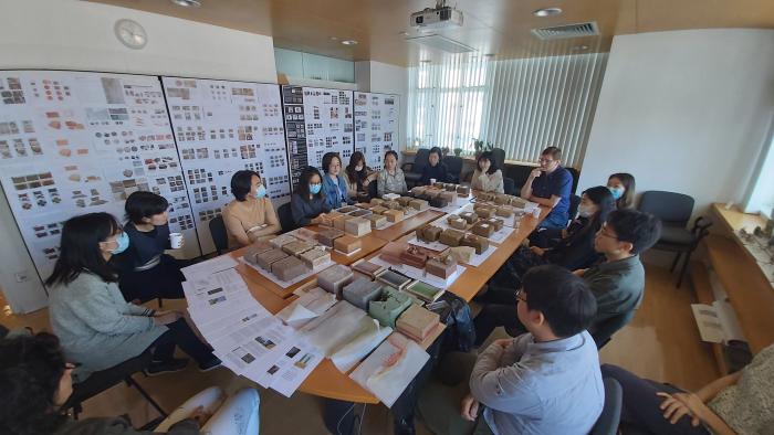 Students sitting down looking at table full of architecture materials