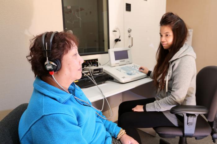 一位女士正在與旁邊的助手進行聽力測試
