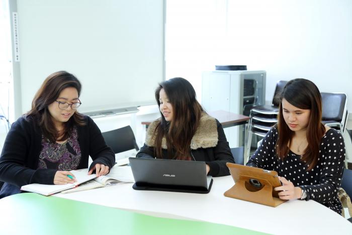 Three female students are studying in a room 