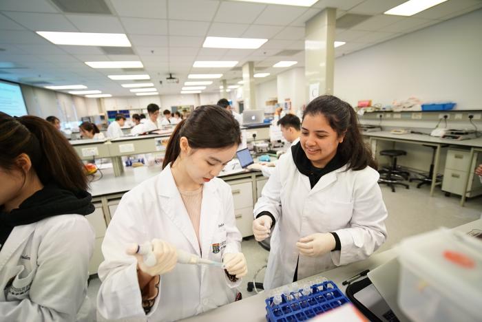 Students wearing lab coat working with equipment in lab