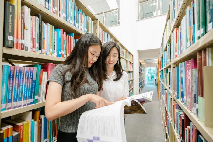 學生在圖書館指著一本打開的書