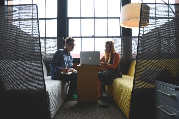 Male and female students looking at laptop while sitting