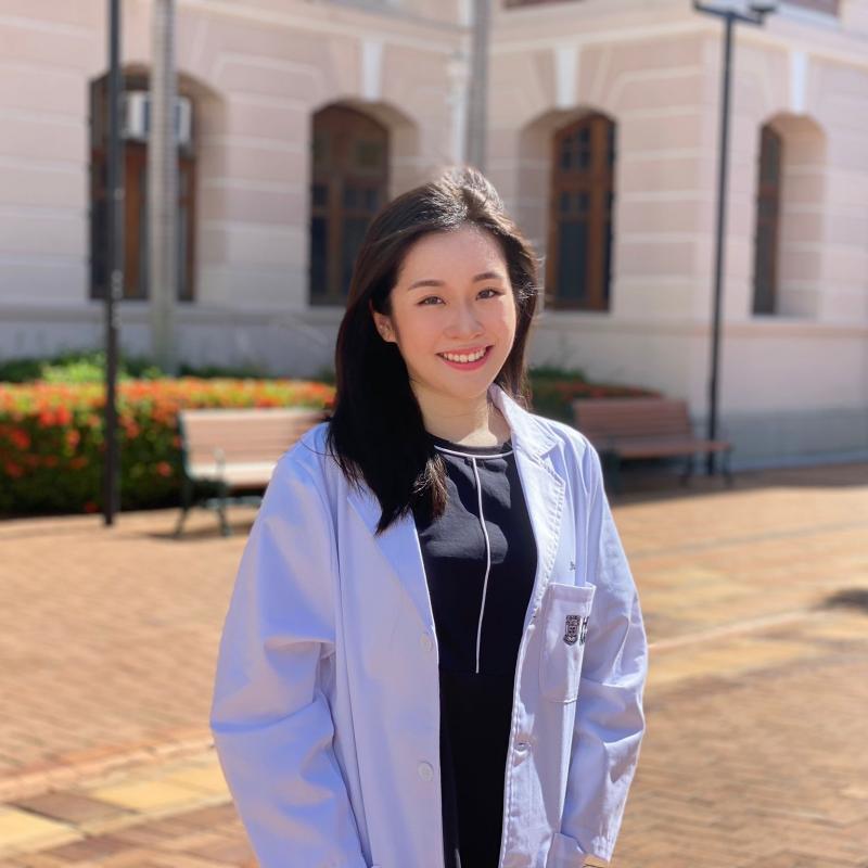 A girl wearing white coat standing near a building